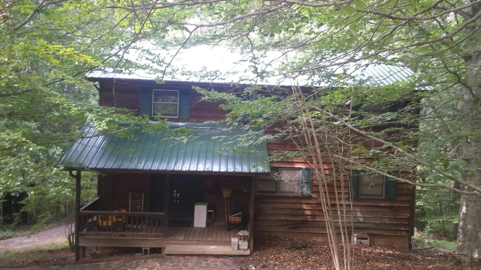 Green metal roof and covered porch on a log cabin in Todd