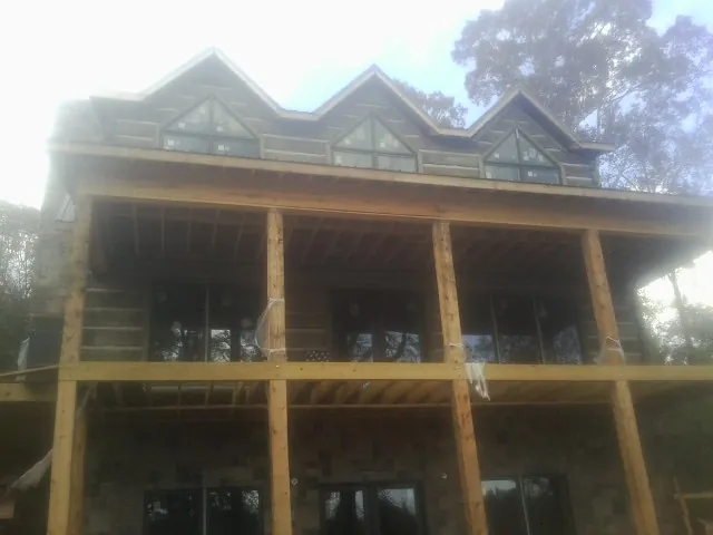 Dormers and porch framing on a large log home under construction — Roof Coating work by our crew in Todd
