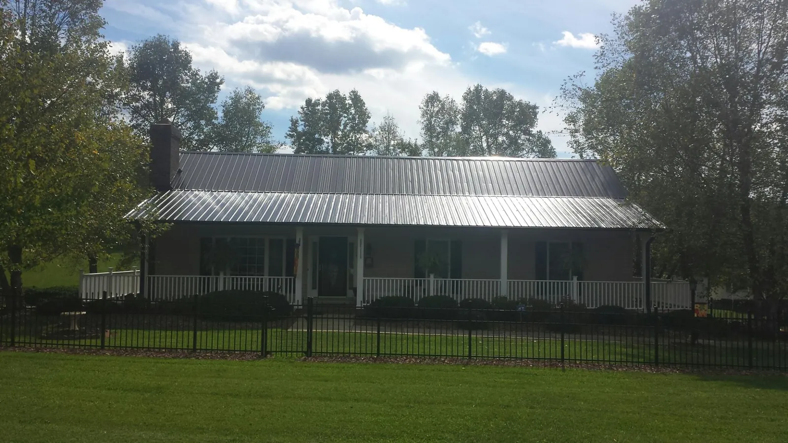 Gray metal roof on a brick ranch with a full width front porch — Gutter Guard Installation work by our crew in Todd